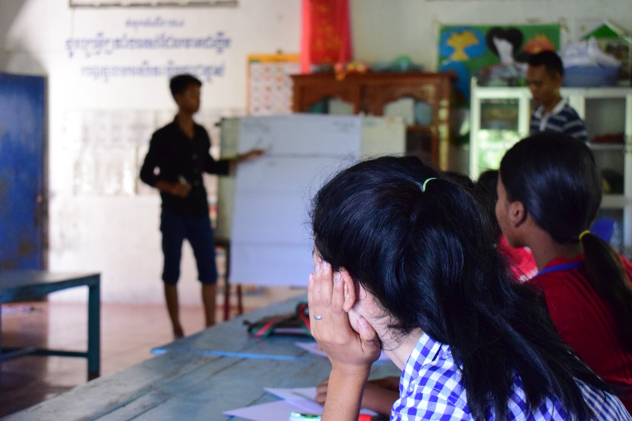 A youth club leader delivers a session at a flipchart, photographed from behind seated participants